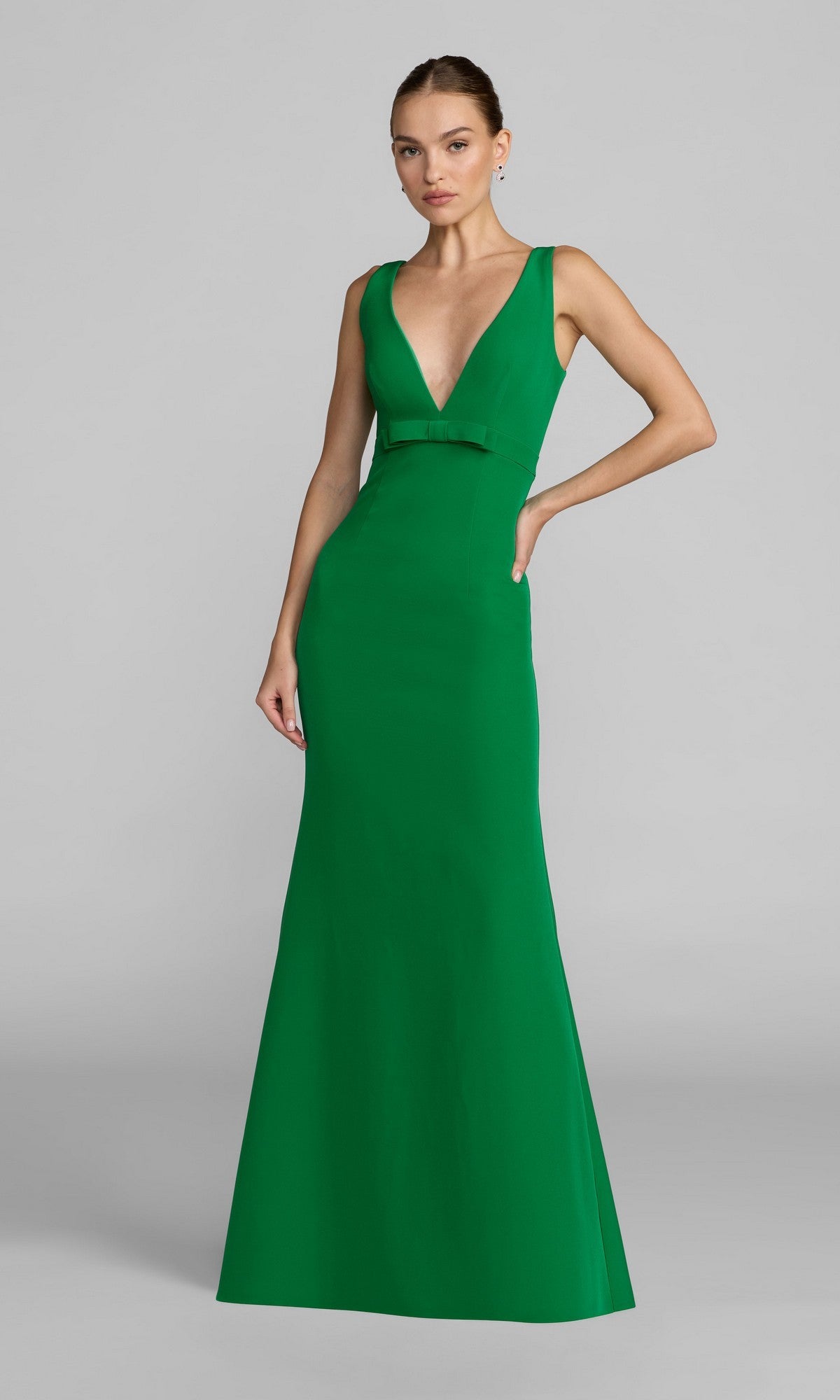 A woman models the Mac Duggal 2371 Long Formal Dress, a sleeveless green crepe evening gown with a V-neckline and waist belt, against a plain gray background.